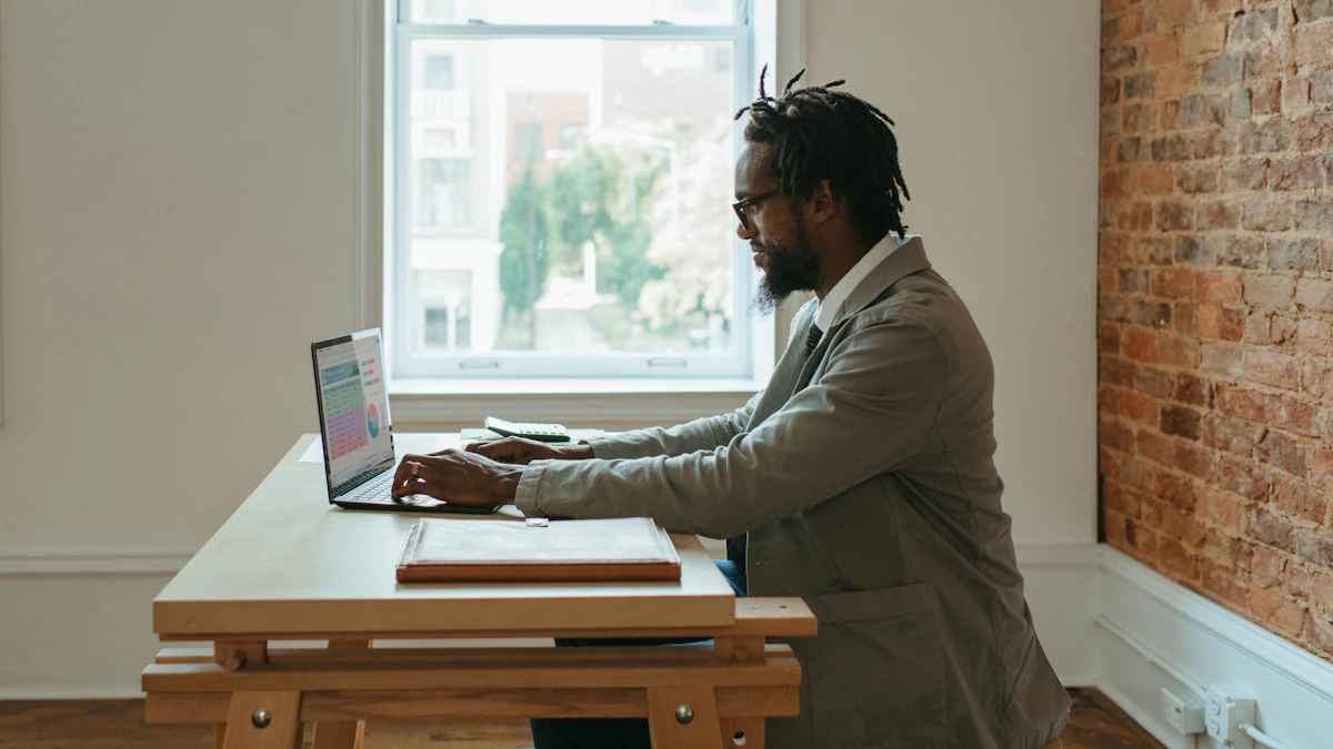 A person working on a laptop beside a sunlit office window