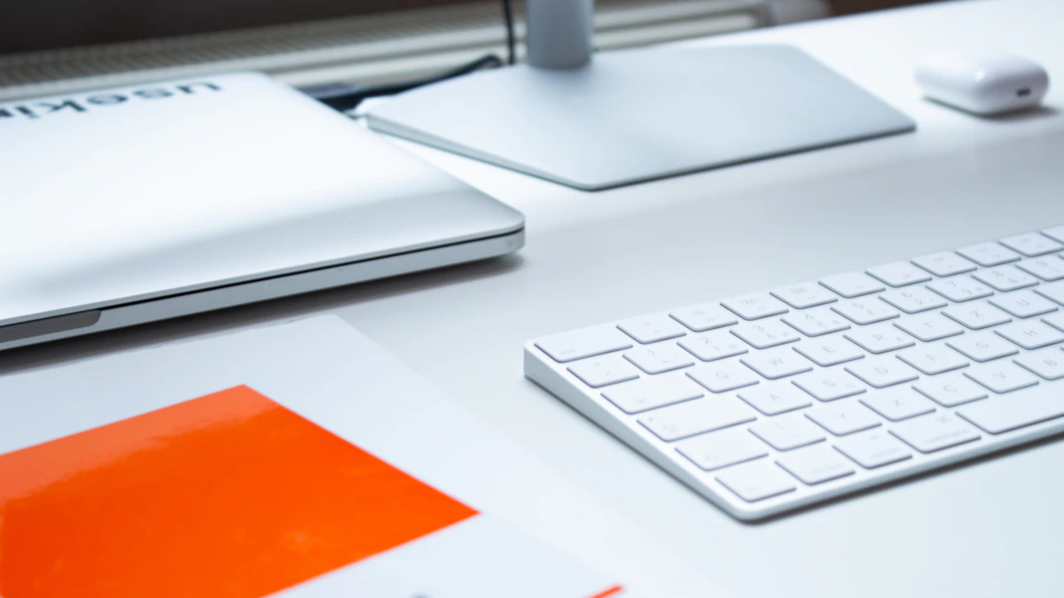 A clean workspace with a laptop, keyboard, and notebook